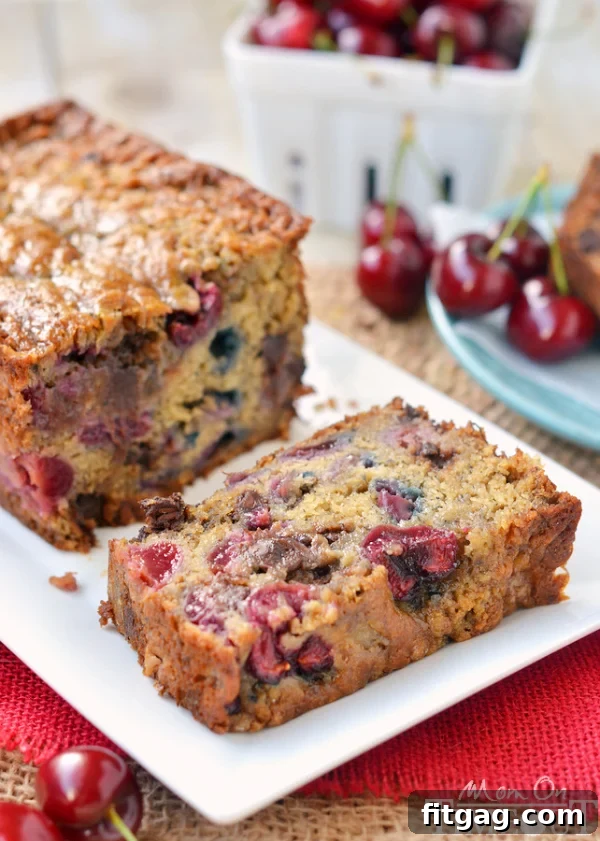 A beautiful loaf of Chocolate Cherry Banana Bread, generously studded with chocolate chips and halved cherries.