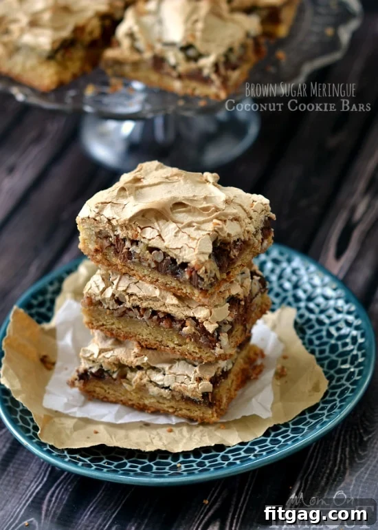 A delectable Brown Sugar Meringue Coconut Cookie Bar slice on a plate, showing the layers of cookie, chocolate, coconut, and meringue.