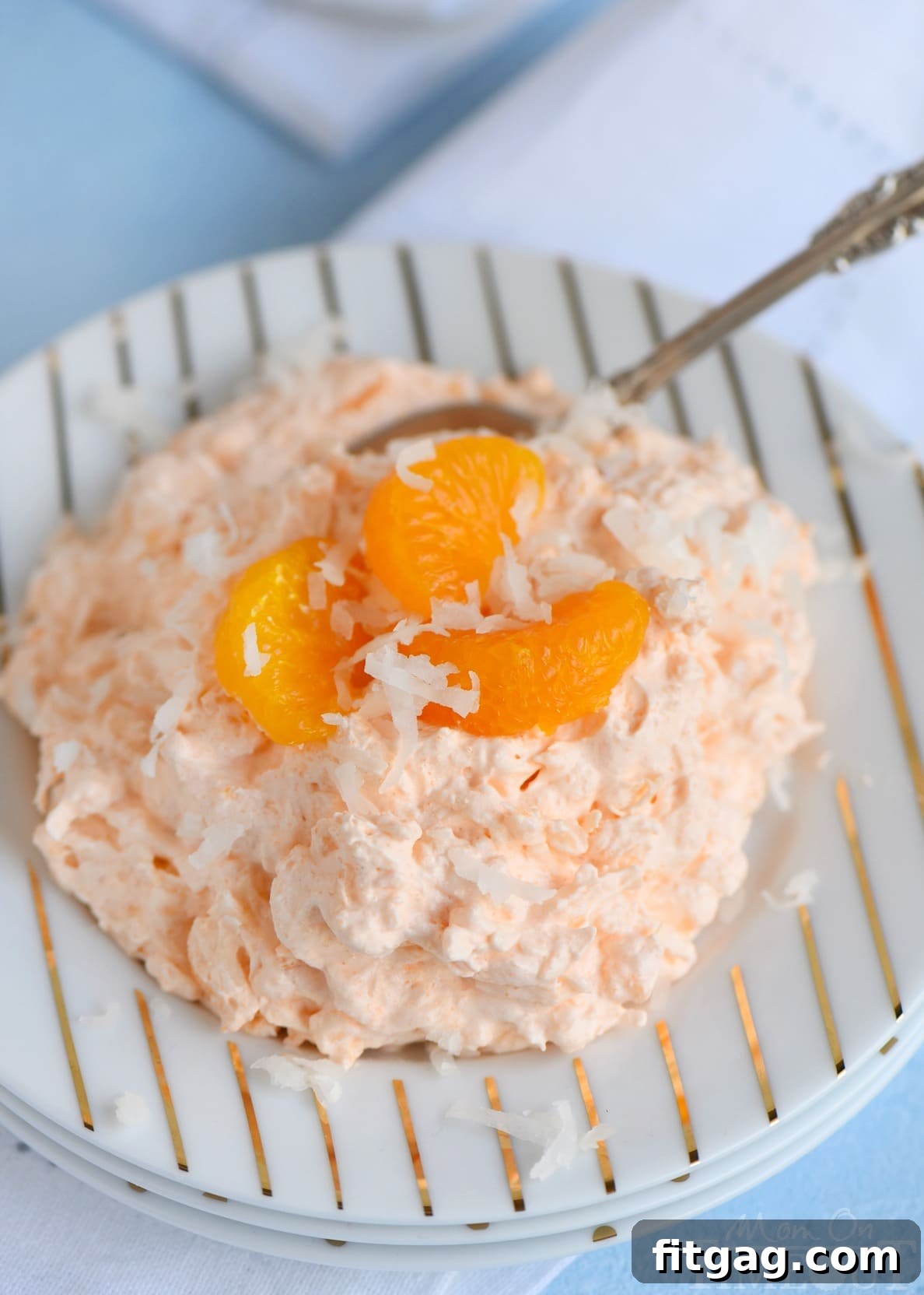 Close-up of Tropical Orange Jello Salad in a glass bowl, showcasing its creamy texture and vibrant color. Ideal for any summer celebration.