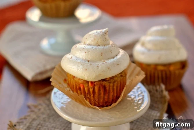 Close-up of baked Pumpkin Carrot Cake Cupcakes topped with creamy Maple Cream Cheese Frosting and a sprinkle of pumpkin pie spice.