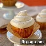 Final Pumpkin Carrot Cake Cupcakes with Maple Cream Cheese Frosting, garnished with a light spice dusting.
