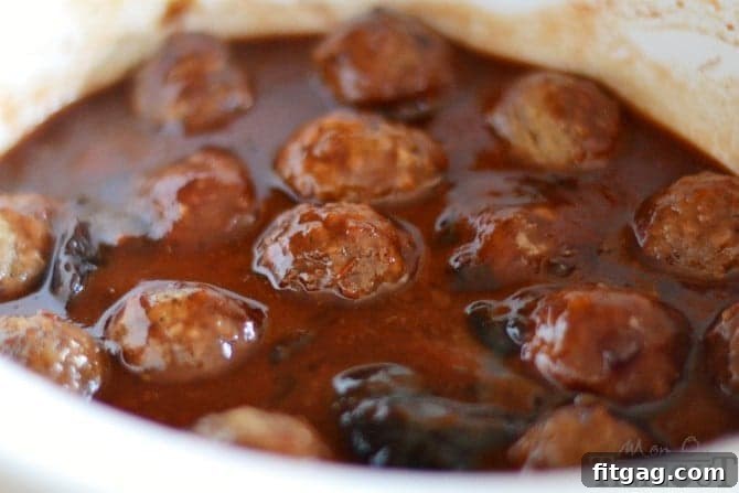 Crock-Pot Party Meatball Bites 3 Close-up of frozen cocktail meatballs simmering in a rich, glossy sauce inside a slow cooker.