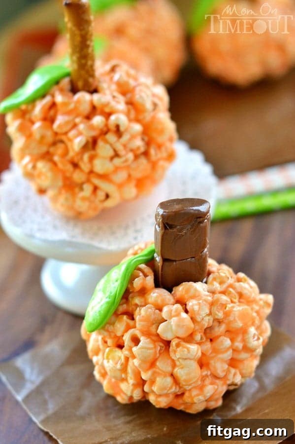 Autumn Pumpkin Popcorn Bites 3 Close-up of fluffy Pumpkin Popcorn Balls, highlighting their soft texture and decorative pretzel stems.