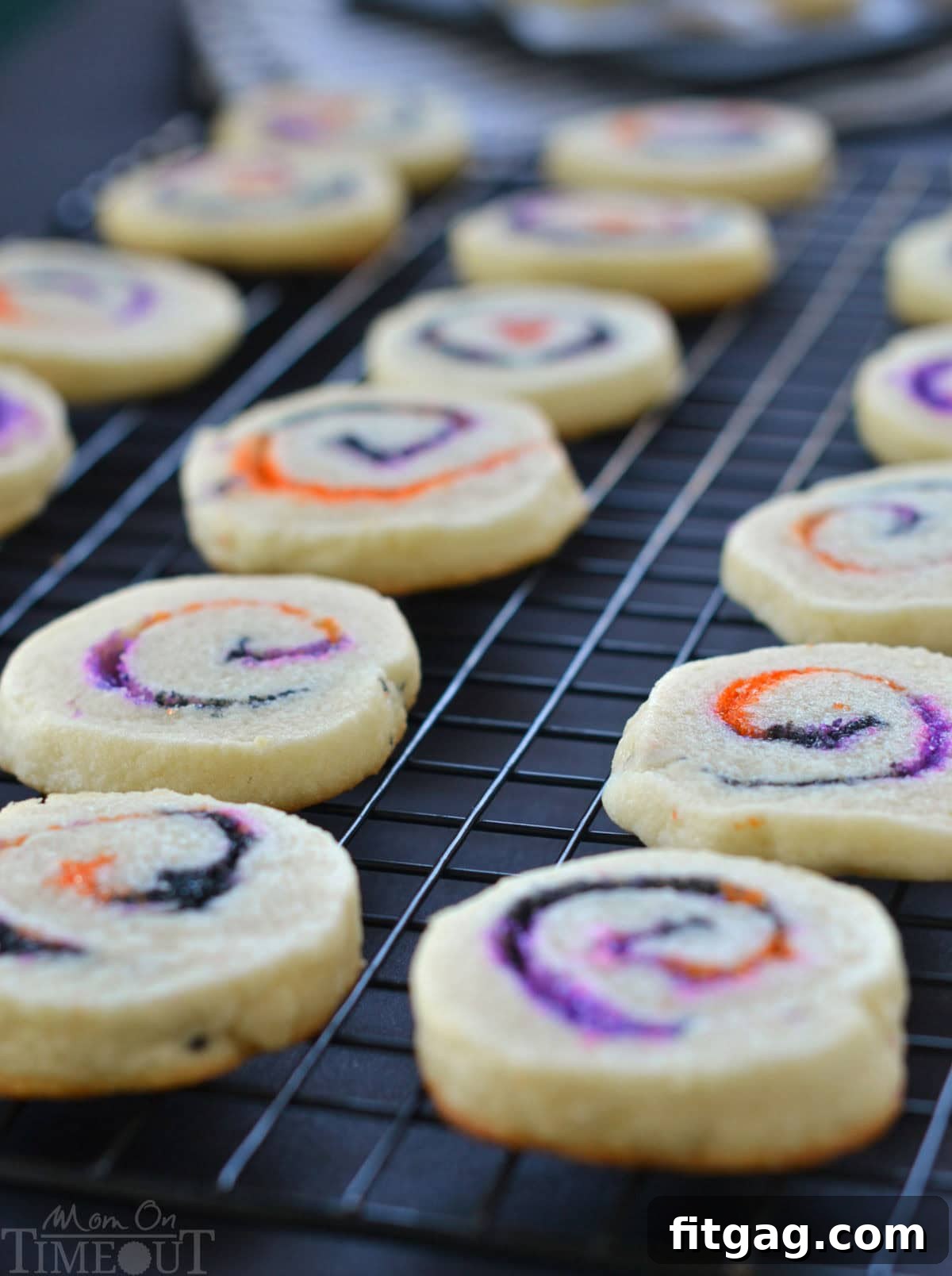 Cookies cooling on black wire rack. Orange, black and purple sugar swirls are clearly visible in the halloween cookies.