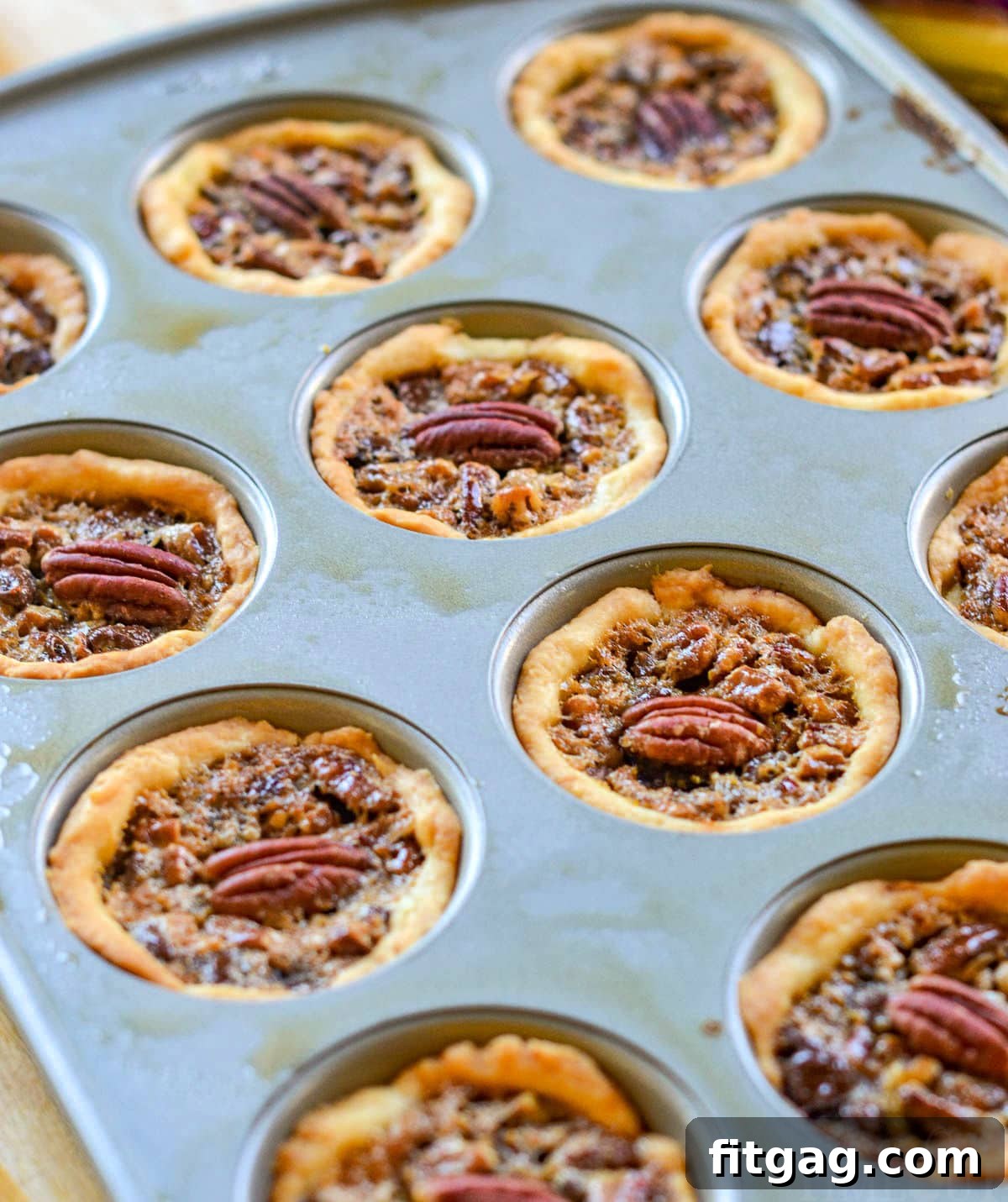 Pecan Pie Bites 5 Freshly baked mini pecan pies, golden and glistening, still cooling within the muffin pan. This image showcases the delicious final product before removal.