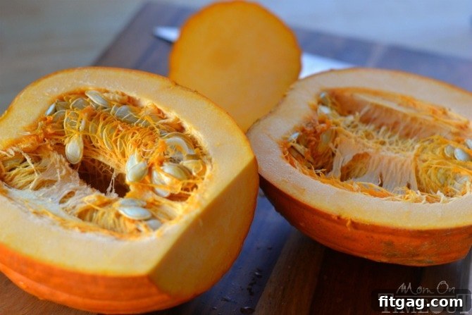 A fresh pumpkin cut in half, revealing its seeds and fibrous strands, ready to be scooped clean for slow cooker pumpkin puree.