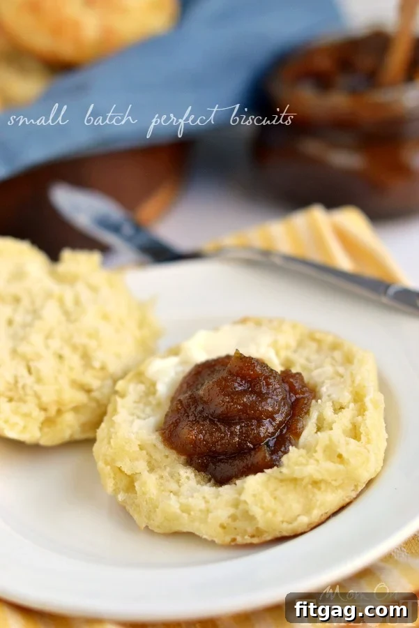 Homemade Biscuits with Sweet Pumpkin Butter A golden-brown small batch biscuit topped with a generous dollop of pumpkin butter, resting on a white plate with a fork.