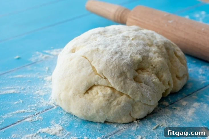 Preparing Homemade Biscuit Dough for Baking Biscuit dough rolled out on a floured surface with a wooden rolling pin, ready for cutting into perfect small batch biscuits.