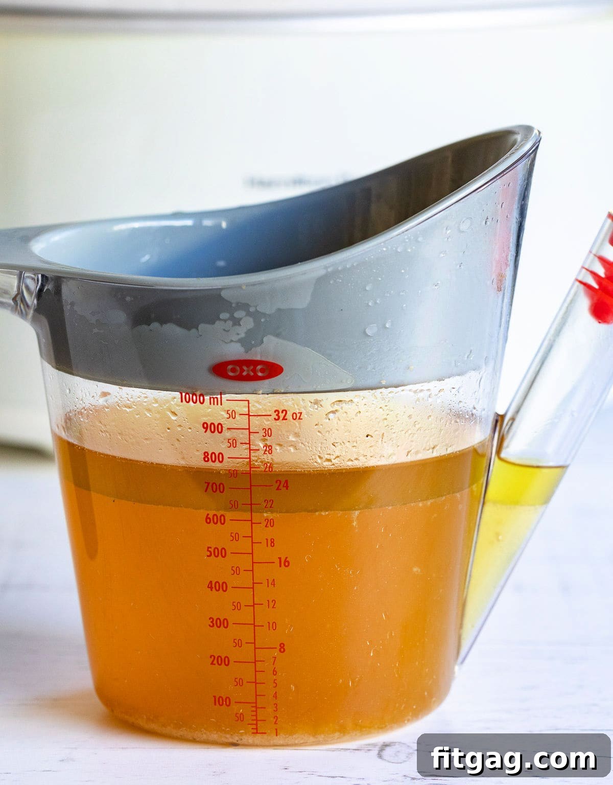 A clear gravy fat separator clearly illustrating the distinct layers, with the golden fat visibly separated and floating at the top, while the darker, flavorful turkey drippings settle at the bottom.
