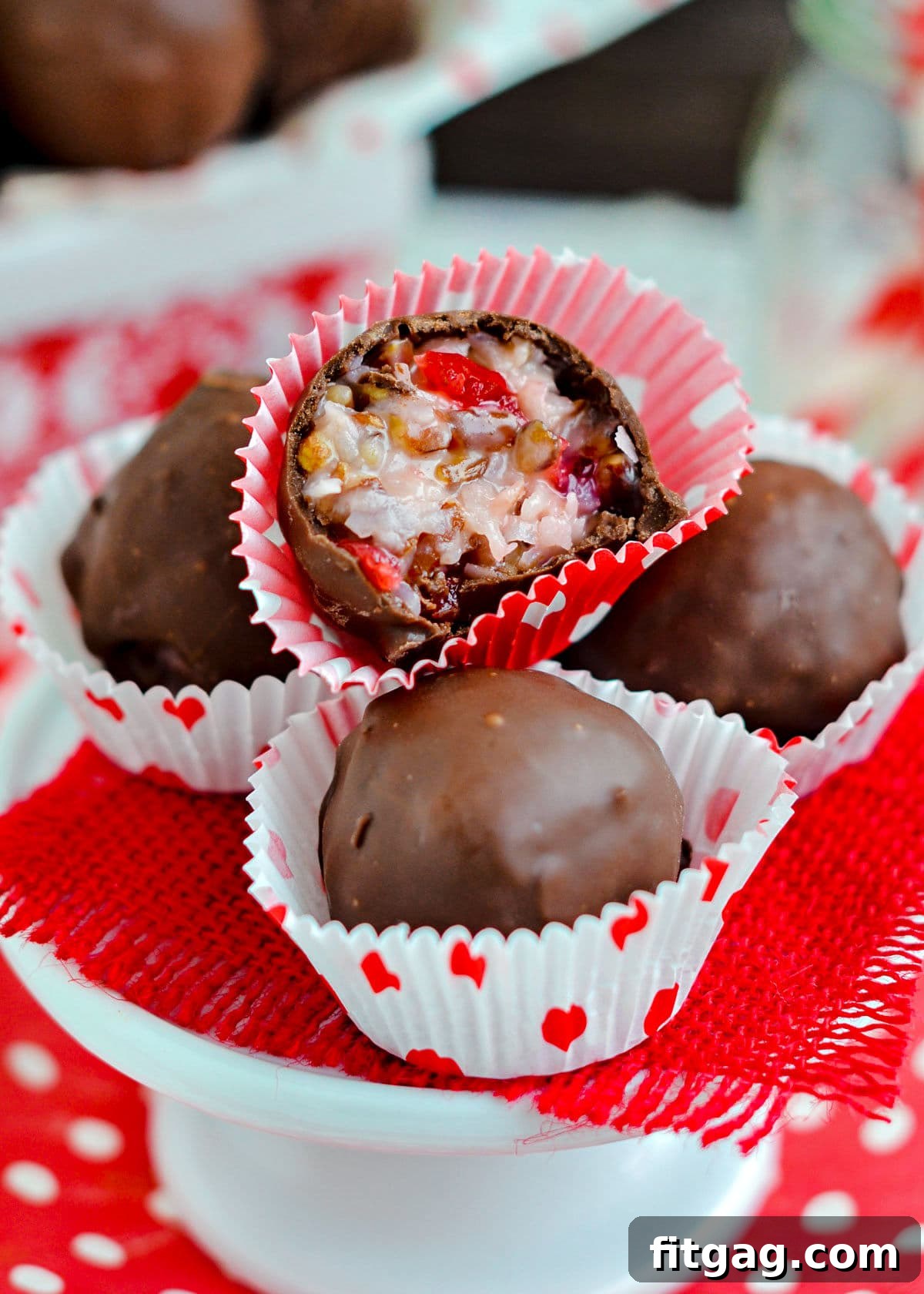 First Lady's Coconut Delights 2 Four Martha Washington candies, one cut in half revealing the rich coconut, pecan, and cherry interior, arranged on a small cupcake stand with red burlap.