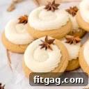 pile of eggnog cookies on wood cutting board. cookies have been frosted with eggnog frosting in a thick swirl and are garnished with anise.