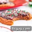 cookie with bite out of it sitting on white surface with more chocolate cookies in background