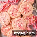 peppermint cookies piled high on a parchment lined baking sheet with candy canes scattered about.