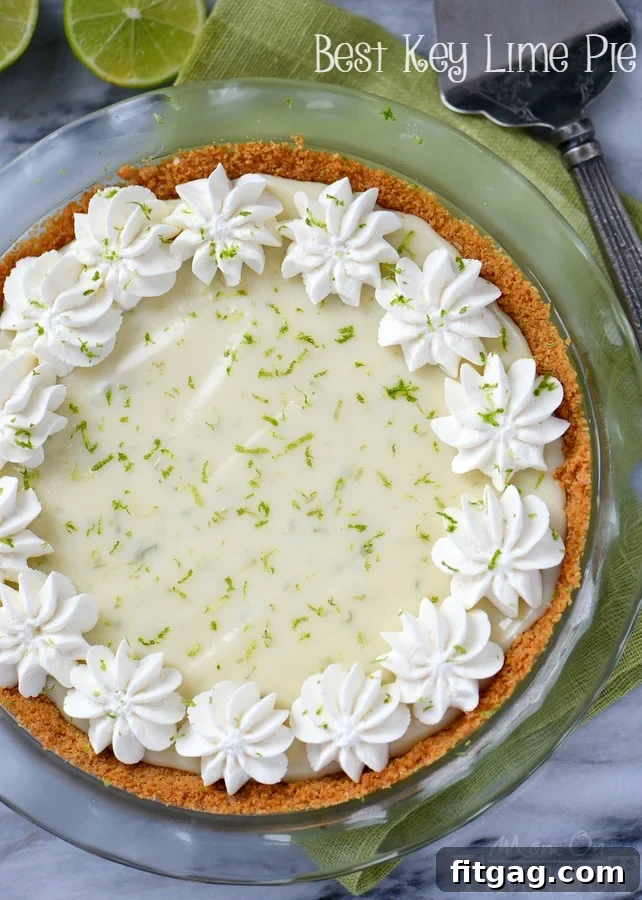 A close-up of a whole Key Lime Pie, showcasing the golden-brown graham cracker crust and the smooth, pale green filling, ready to be sliced.