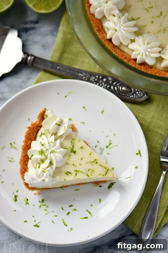 A perfect slice of Key Lime Pie, showcasing its vibrant green filling, crisp graham cracker crust, and a dollop of whipped cream on top, garnished with lime zest.