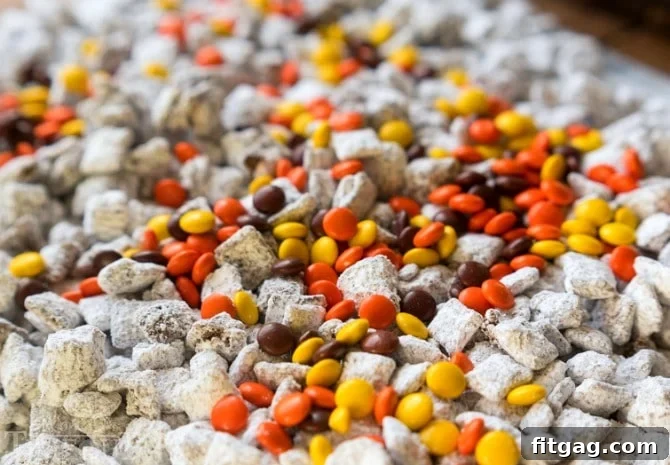Reese's Muddy Buddies spread out, generously topped with Reese's Pieces for color and extra flavor.