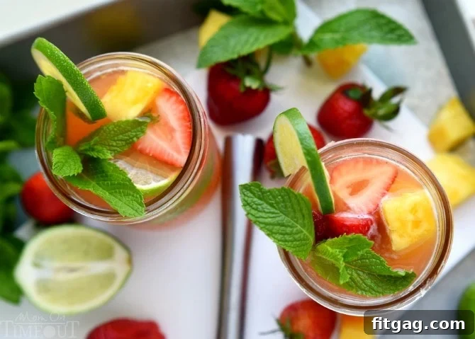 A close-up of a sparkling Pineapple Strawberry Mojito cocktail in a glass, featuring muddled fruit, mint, and a beautiful blend of tropical flavors. The drink looks cool and inviting.