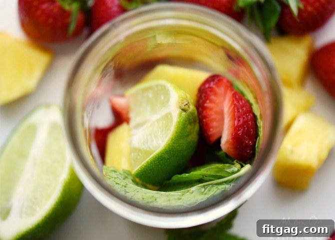 A close-up shot of muddled strawberries, pineapple, mint, and lime in the bottom of a glass, showing the vibrant colors and juices released, a crucial step for a flavorful mojito.