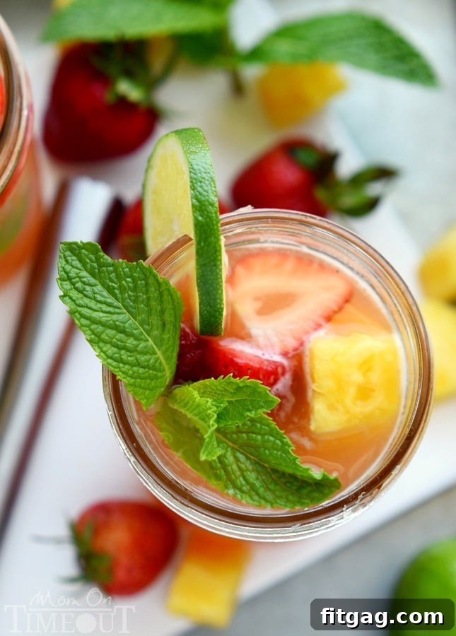 A beautifully assembled Pineapple Strawberry Mojito cocktail, garnished with a lime slice and fresh mint leaves, showcasing its vibrant colors and inviting presentation.