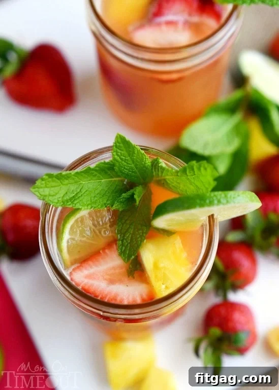 A refreshing Pineapple Strawberry Mojito in a glass, with frozen strawberries serving as ice, keeping the drink perfectly chilled and adding to its vibrant aesthetic. Ideal for summer entertaining.