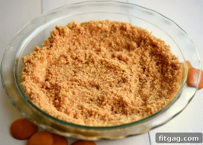 Pressing the Nilla Wafer pie crust into the pie plate for a firm and sturdy base.