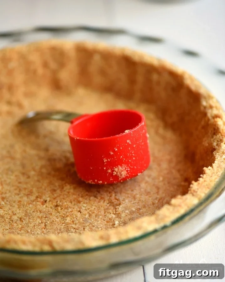 Technique for achieving even sides on a Nilla Wafer pie crust using a measuring cup.