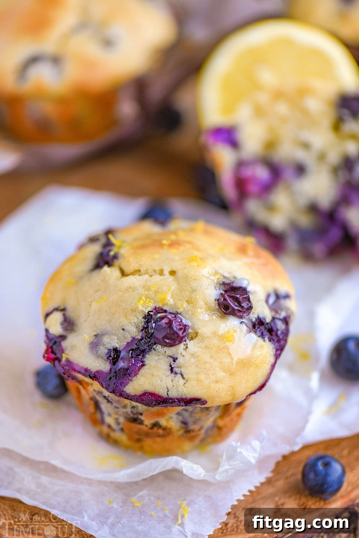 Beautifully glazed Blueberry Lemon Cream Cheese Muffins arranged on white parchment paper, ready to be enjoyed.
