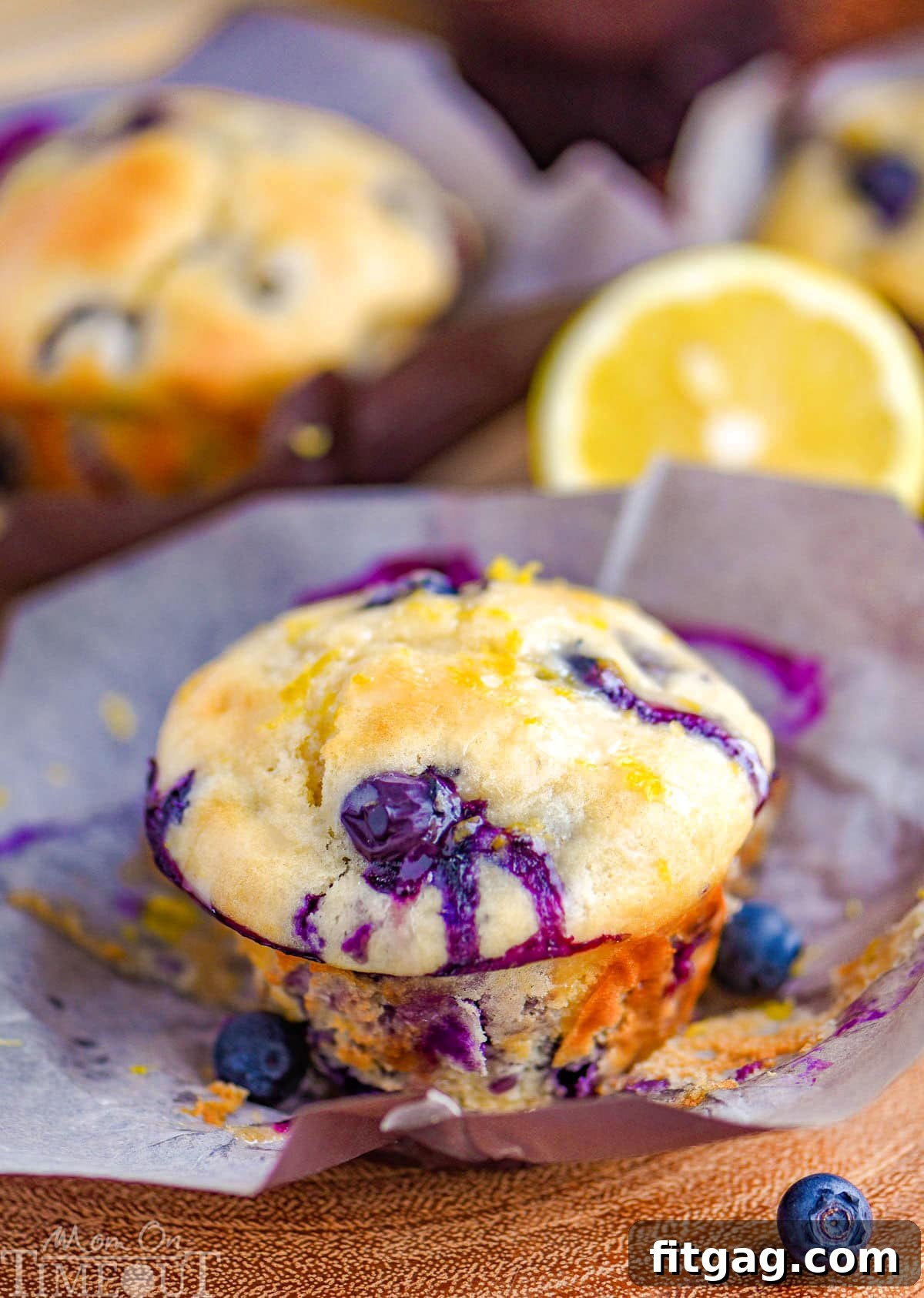 Cream Cheese Stuffed Blueberry Lemon Muffins 7 A beautifully baked Blueberry Lemon Cream Cheese Muffin, topped with a delicate lemon glaze, rests elegantly on a parchment liner, highlighting its tender texture and inviting appeal.
