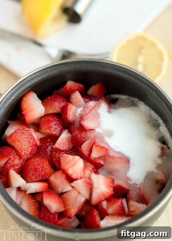 Strawberry ice cream topping ingredients in a saucepan including strawberries and sugar and lemon juice