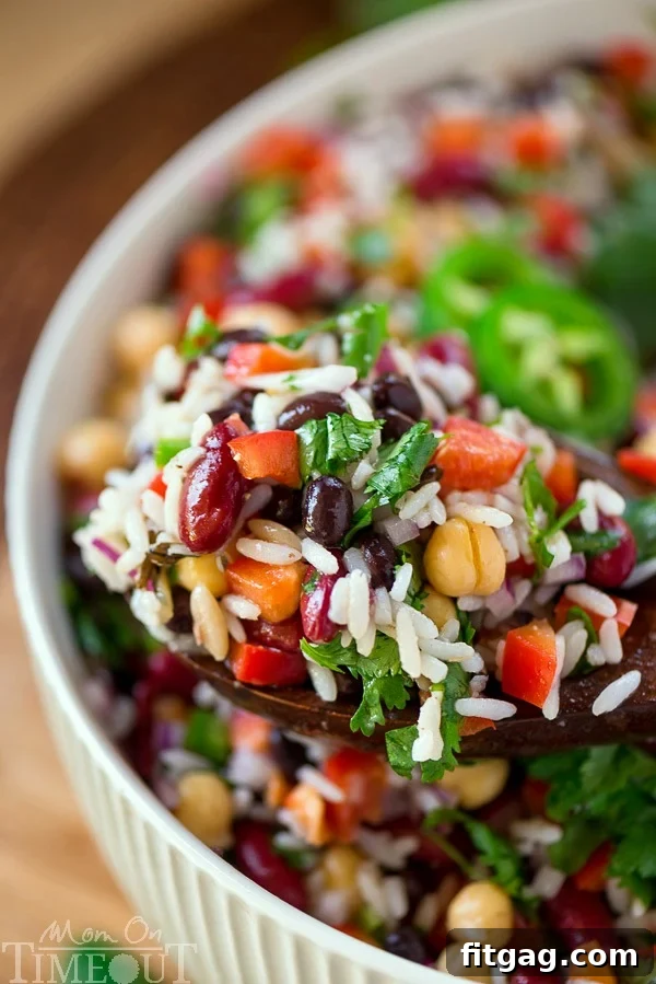 A serving spoon lifting a portion of Wild Rice Three Bean Salad from a large glass bowl, ready to be enjoyed