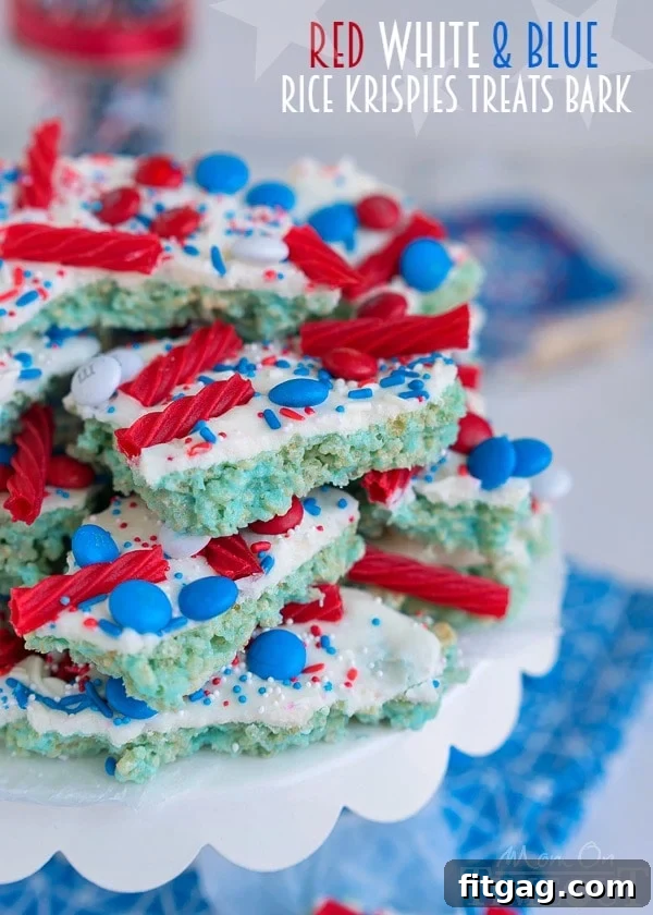 Stacked pieces of Red White and Blue Rice Krispies Treats Bark, showing the distinct layers and colorful sprinkles.