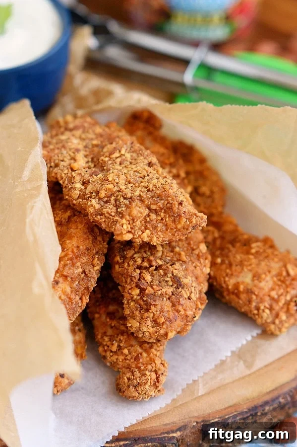 Six baked sriracha almond chicken strips neatly wrapped in parchment paper, ready to serve or store