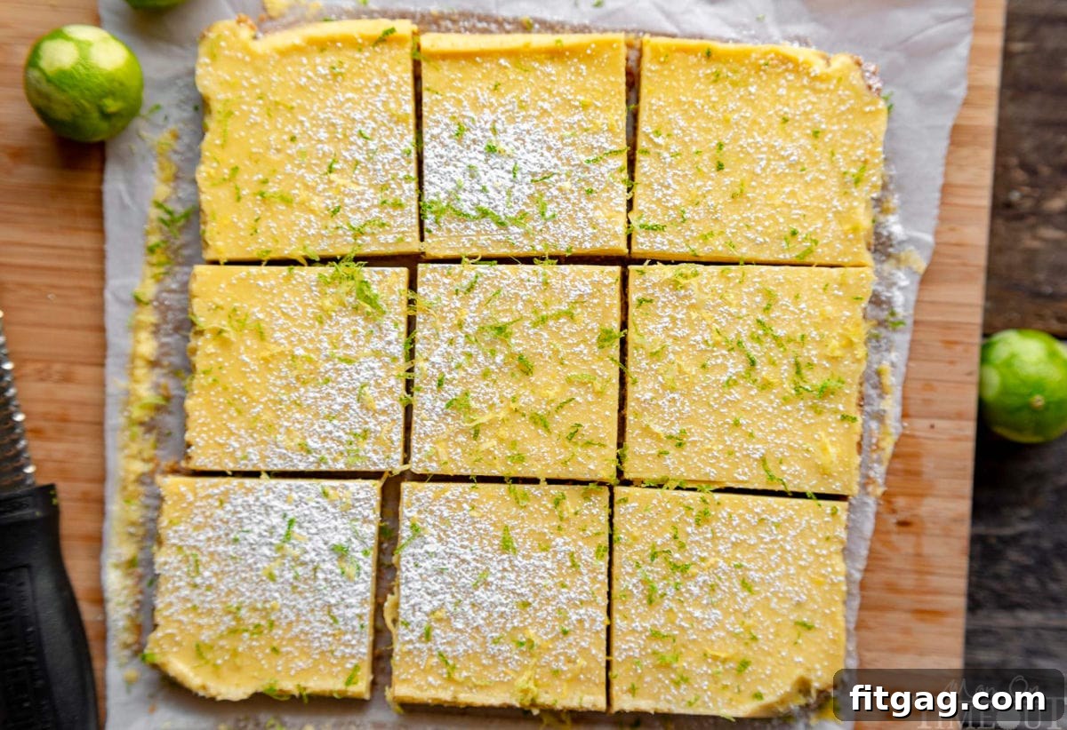 Tangy Key Lime Bars 4 A top-down view of nine perfectly square Key Lime Pie Bars arranged on a rustic wooden cutting board, showcasing their inviting golden crusts and pale green fillings.