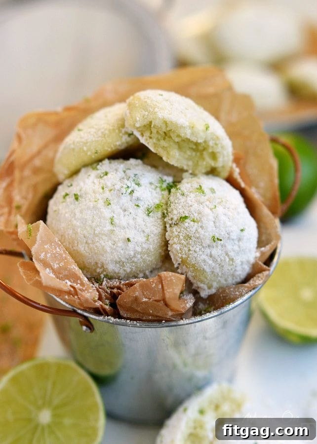Zesty Key Lime Meltaways 4 A batch of freshly baked Key Lime Snowball Cookies, generously dusted with powdered sugar, ready to be enjoyed. A perfect treat for citrus lovers.