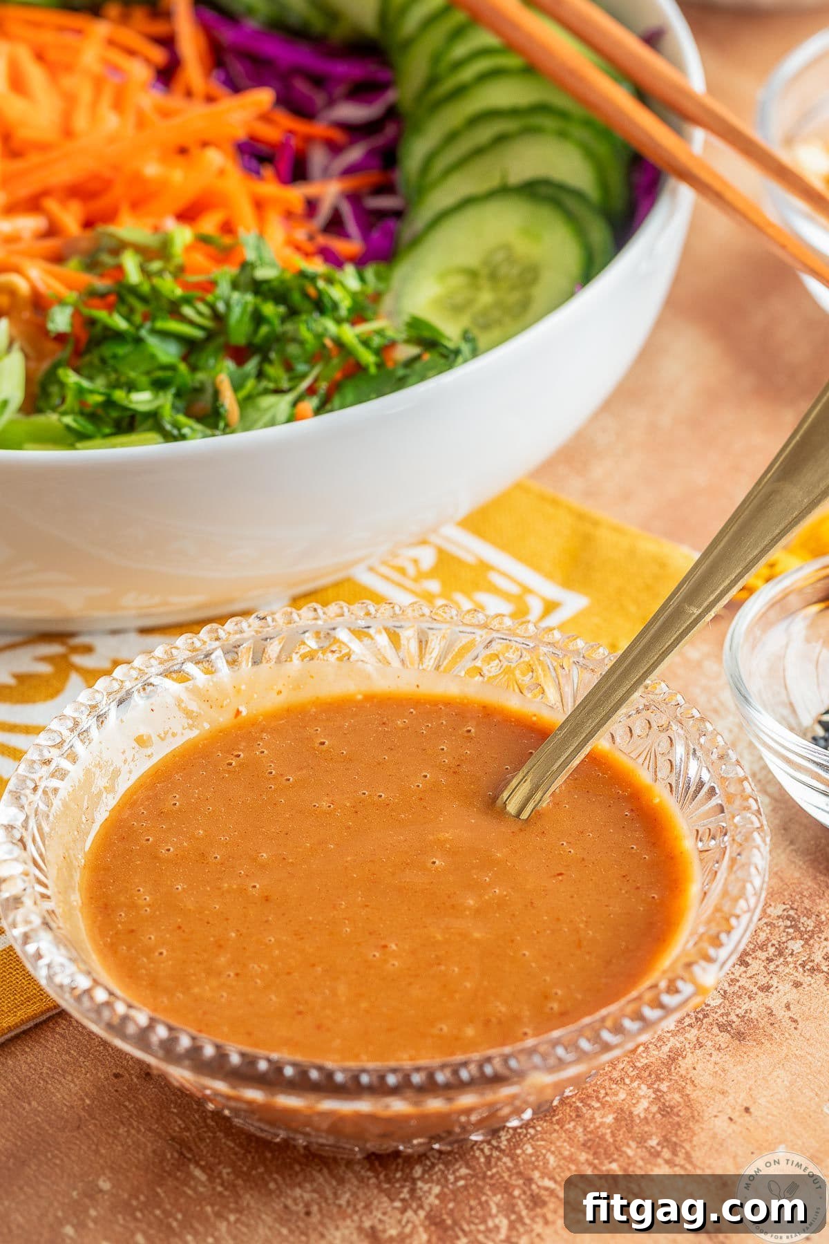 Thai Peanut Salad with Crunchy Veggies and Lime Dressing 4 Thai peanut dressing in a small glass bowl in front of a bowl of salad.